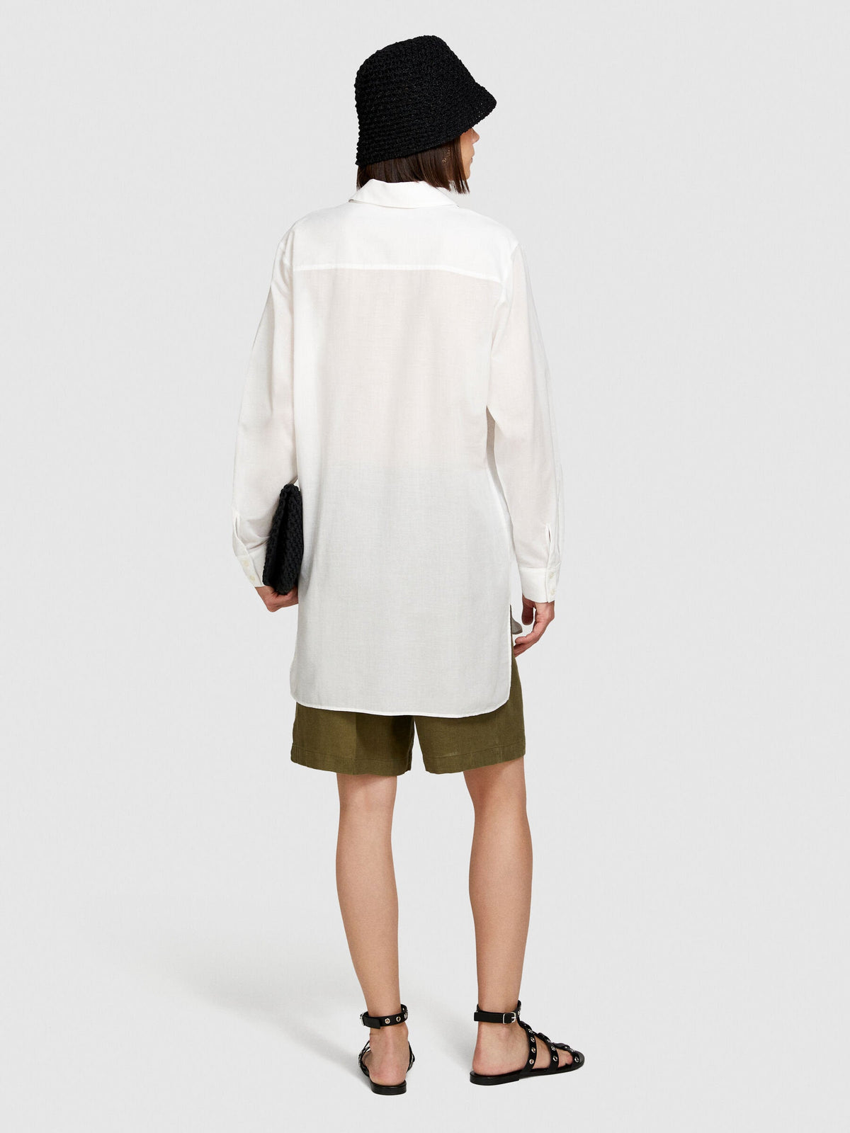 Model posing in an oversized white shirt and khaki shorts.