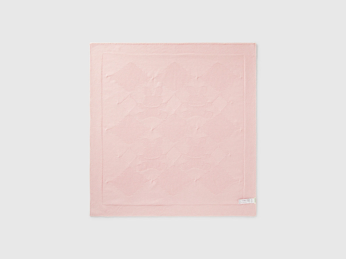 Folded light pink Benetton knit baby blanket, showing textured weave and corner detail.