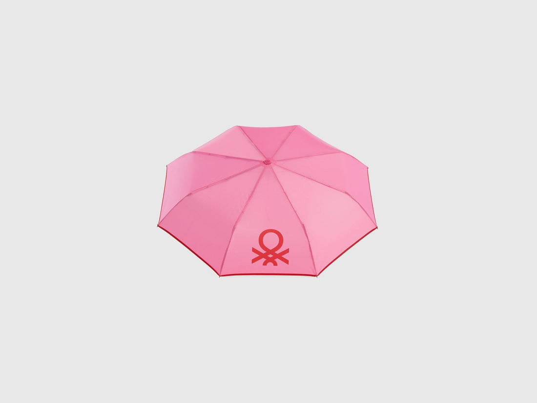 Open pink Benetton umbrella, top view for rain protection.