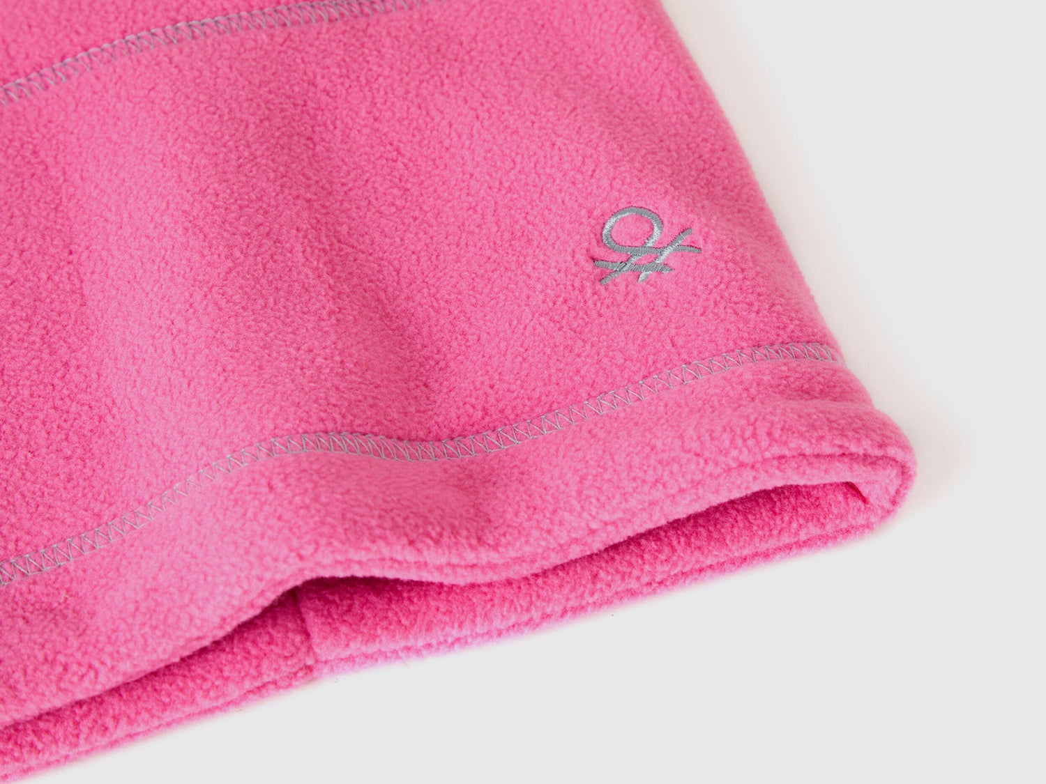 Close-up pink fleece neck warmer with Benetton logo.