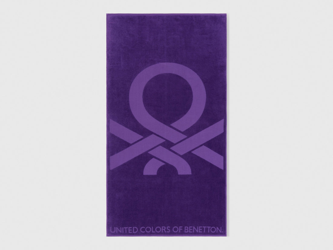 A folded purple beach towel, showing its vibrant color and plush texture.