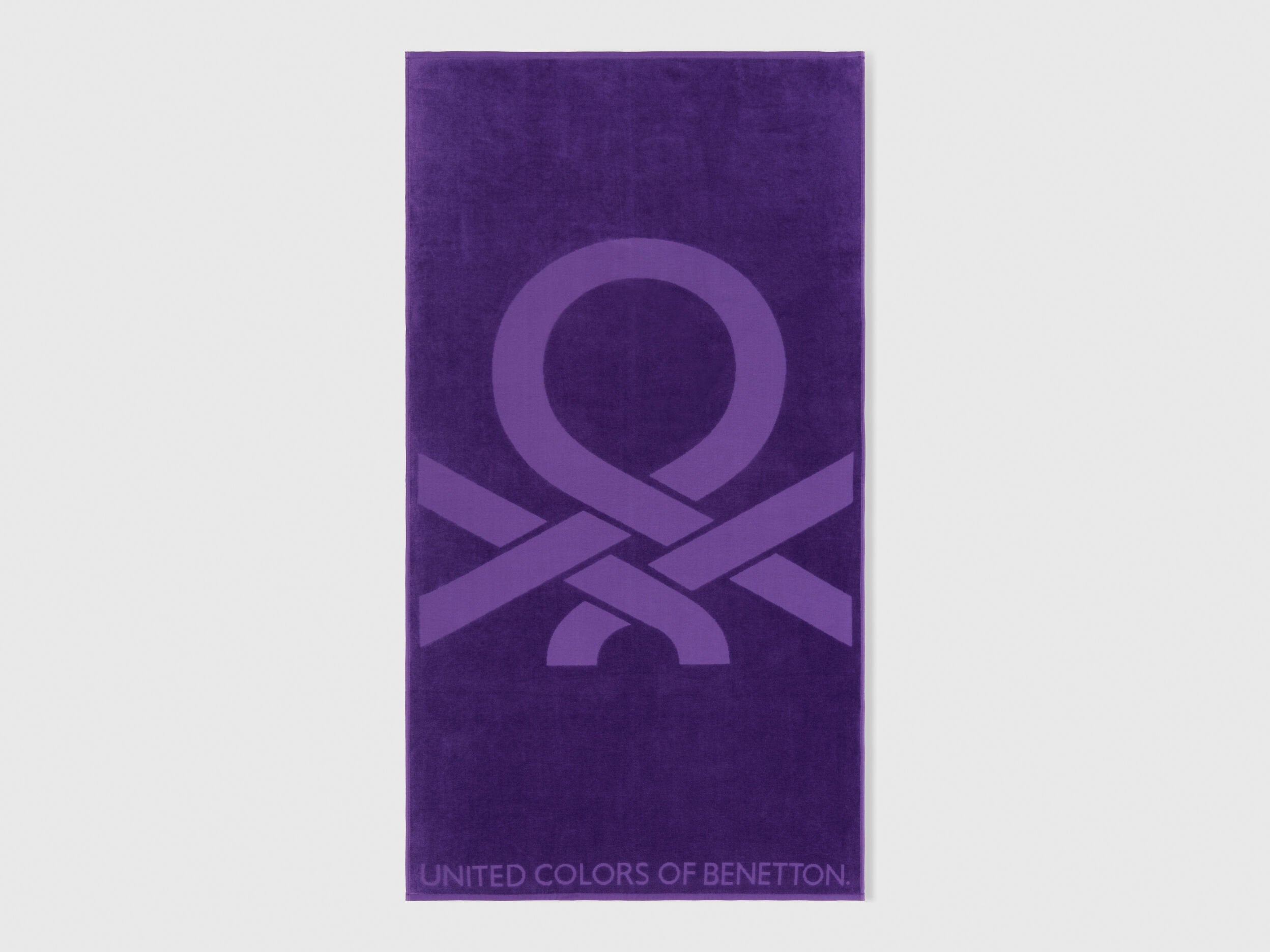 A folded purple beach towel, showing its vibrant color and plush texture.