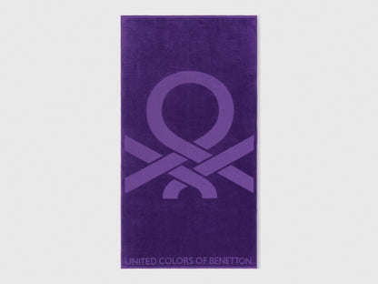 A folded purple beach towel, showing its vibrant color and plush texture.