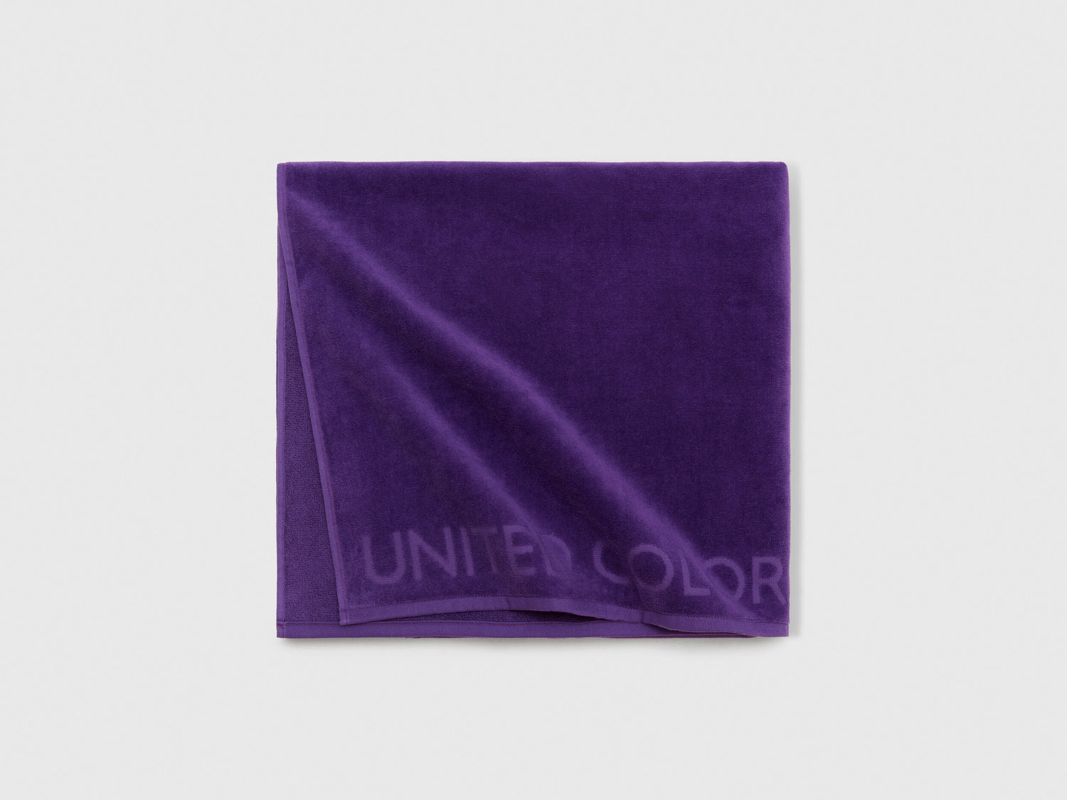 Close-up detail of the soft and absorbent fabric texture of a purple beach towel.
