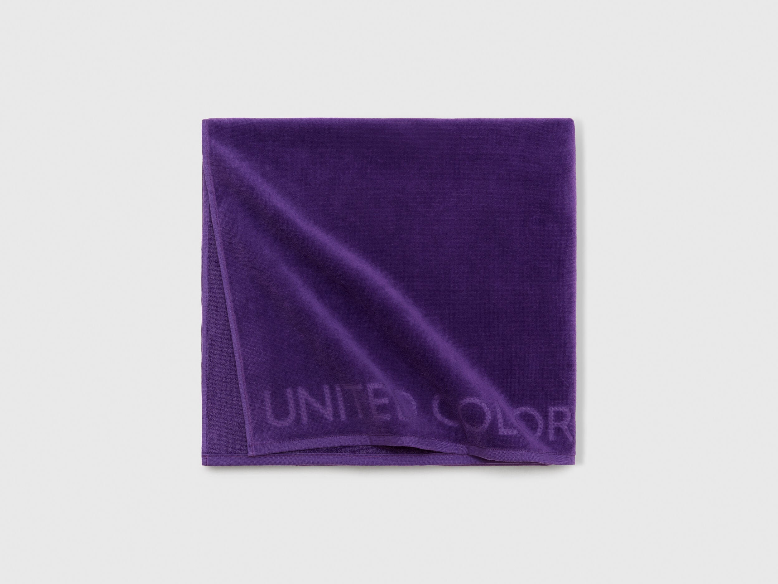 Close-up detail of the soft and absorbent fabric texture of a purple beach towel.