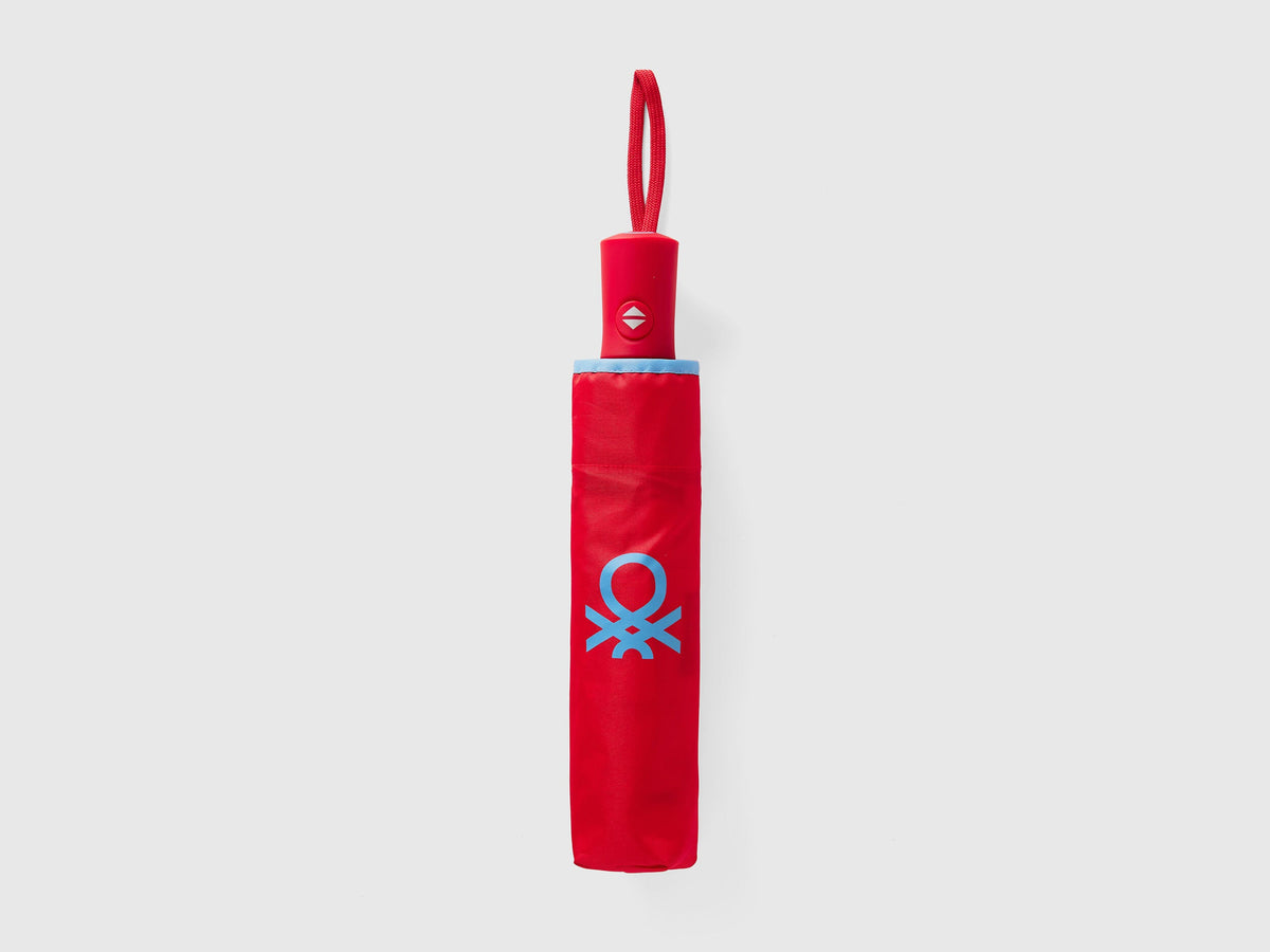 Folded red Benetton umbrella, compact for portability.