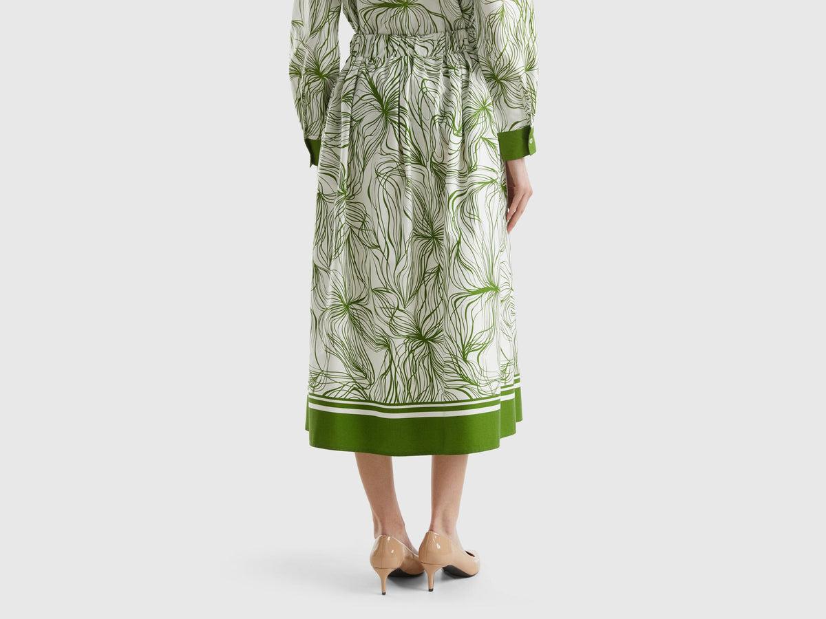 Back view of a sustainable midi skirt in white with green leaf print and a green border.