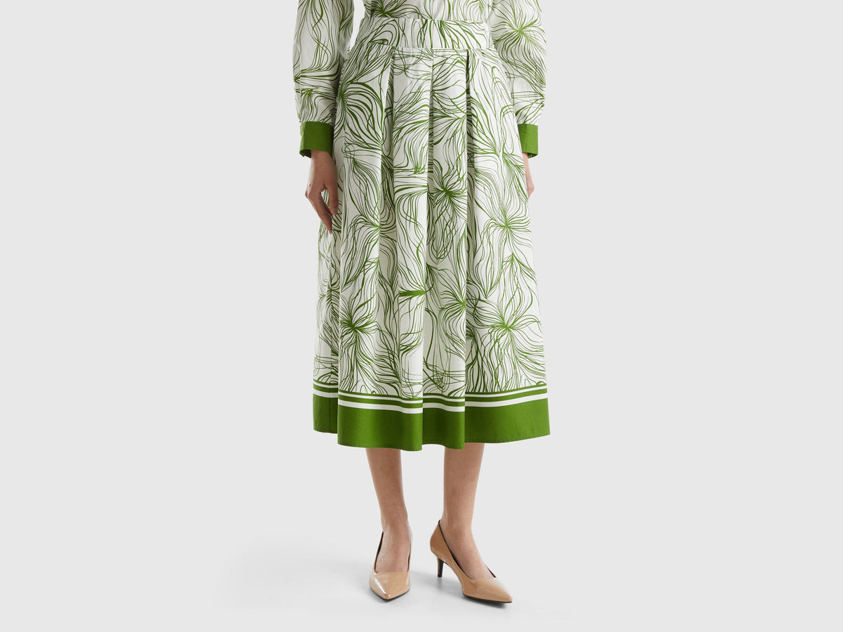 Front view of a sustainable midi skirt in white with green leaf print and a green border.