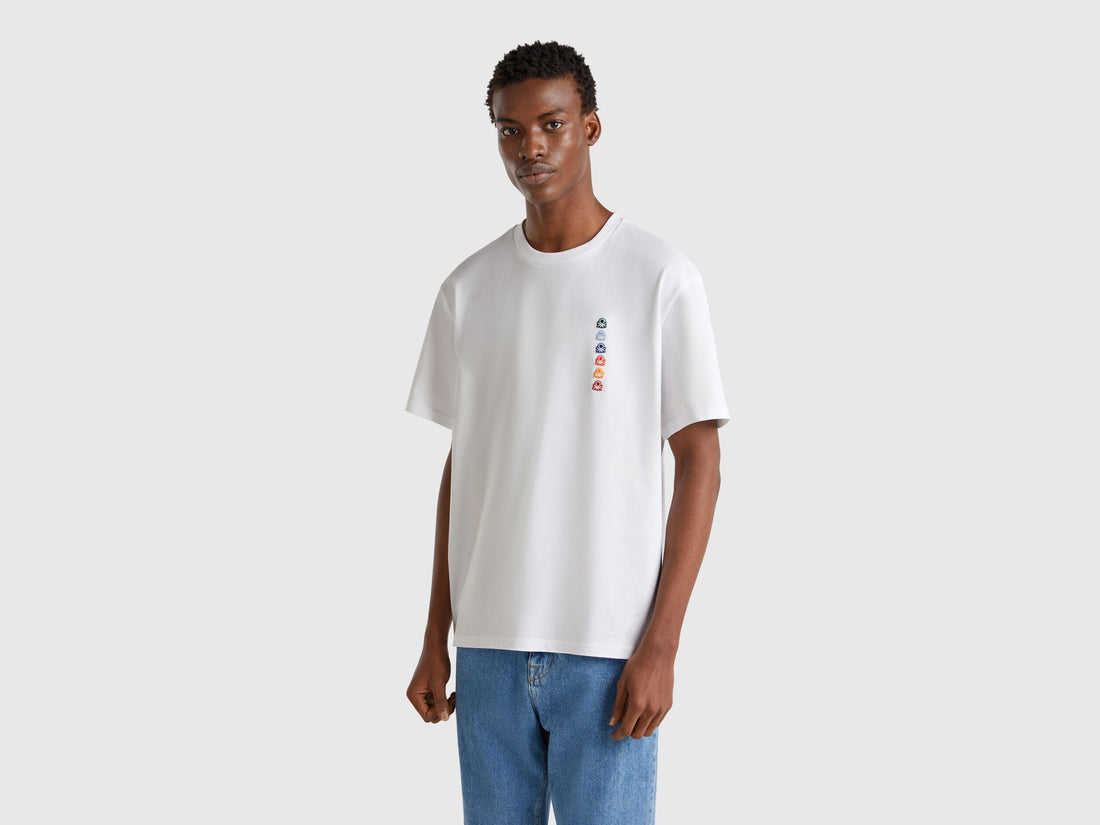 Front view of white Benetton oversized t-shirt with a colorful rectangular logo patch on the chest.