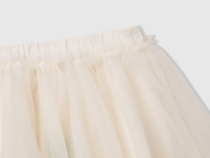 Close-up of the waistband and layered tulle fabric of a white Benetton skirt. Sheer texture.