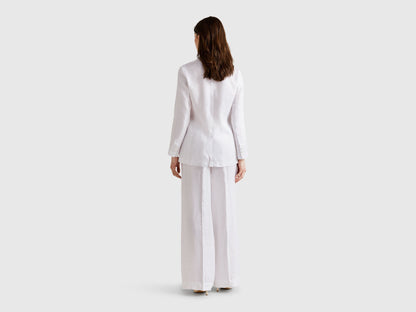 Close-up of a white pure linen Benetton blazer worn by a model, featuring a gold chain necklace and showcasing the blazer&