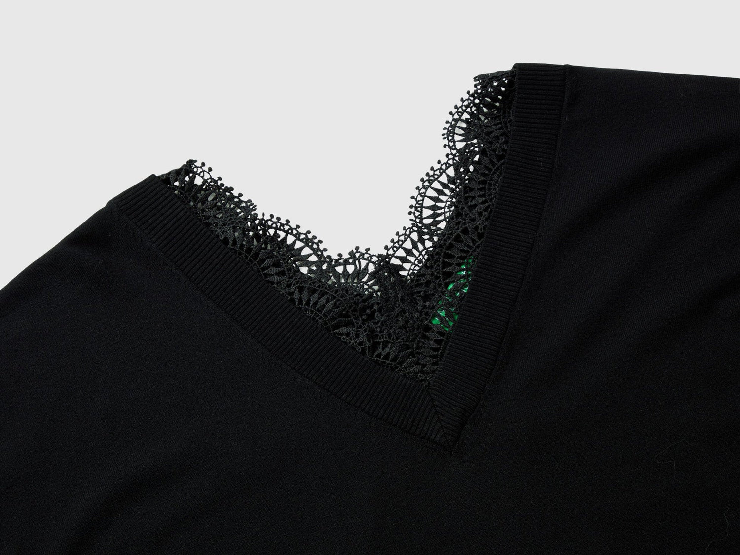Close-up of a black lace top for women, showing the intricate V-neck lace trim.