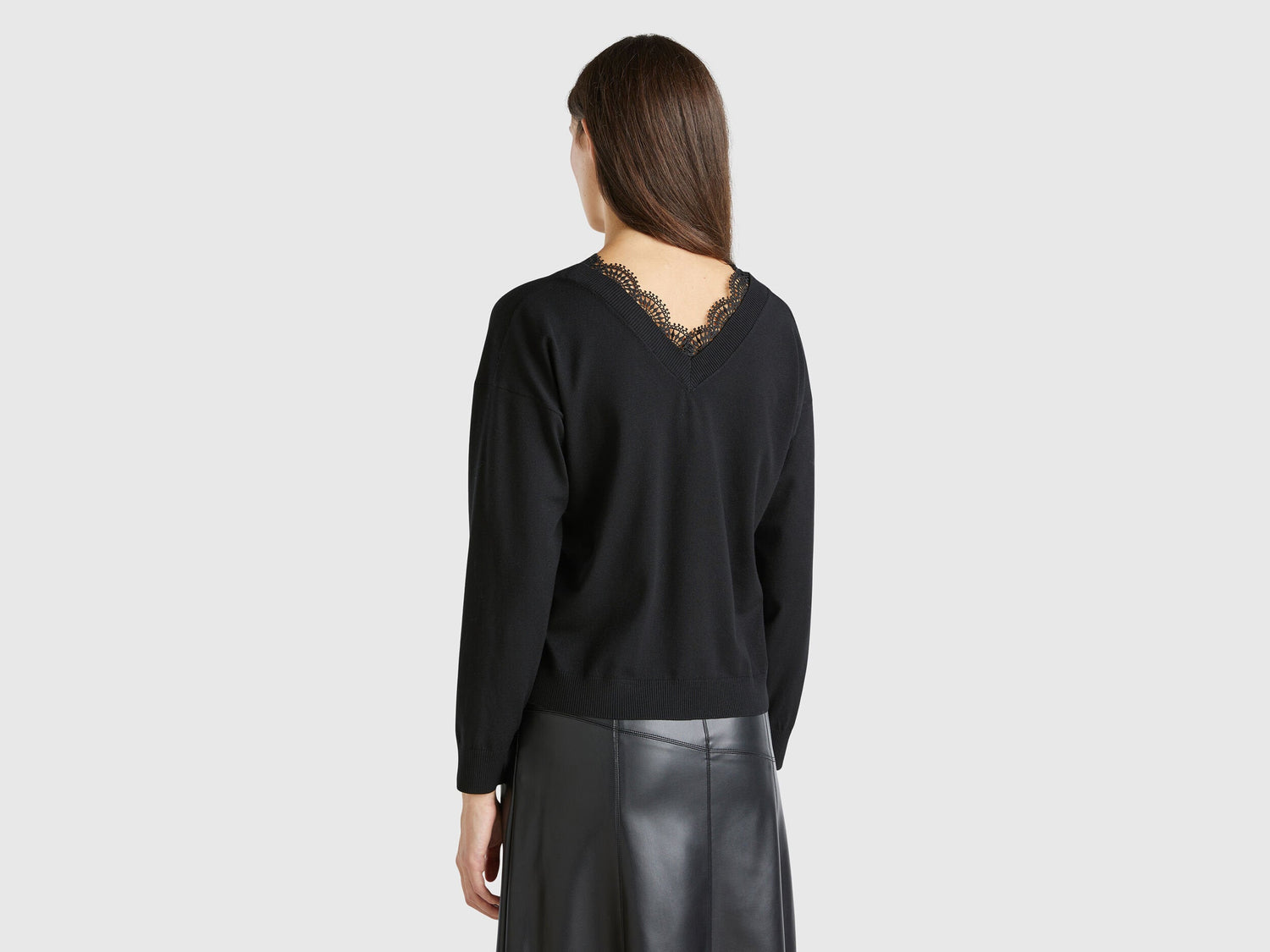 Back view of a woman showcasing a black flowy top with lace detail.