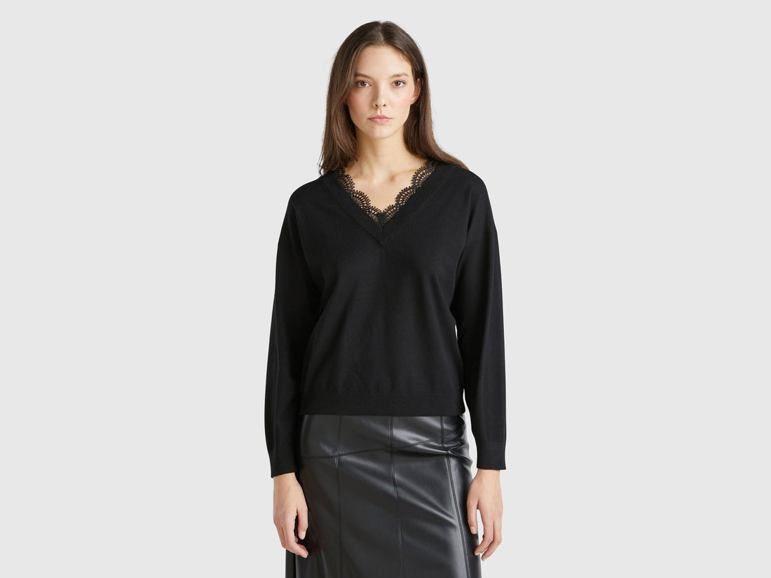 Front view of a woman wearing a black flowy top with lace trim.