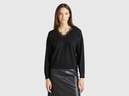 Front view of a woman wearing a black flowy top with lace trim.