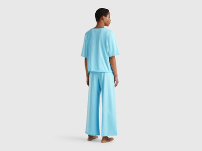  Back view of a woman wearing a light blue loose-fitting pyjama set.