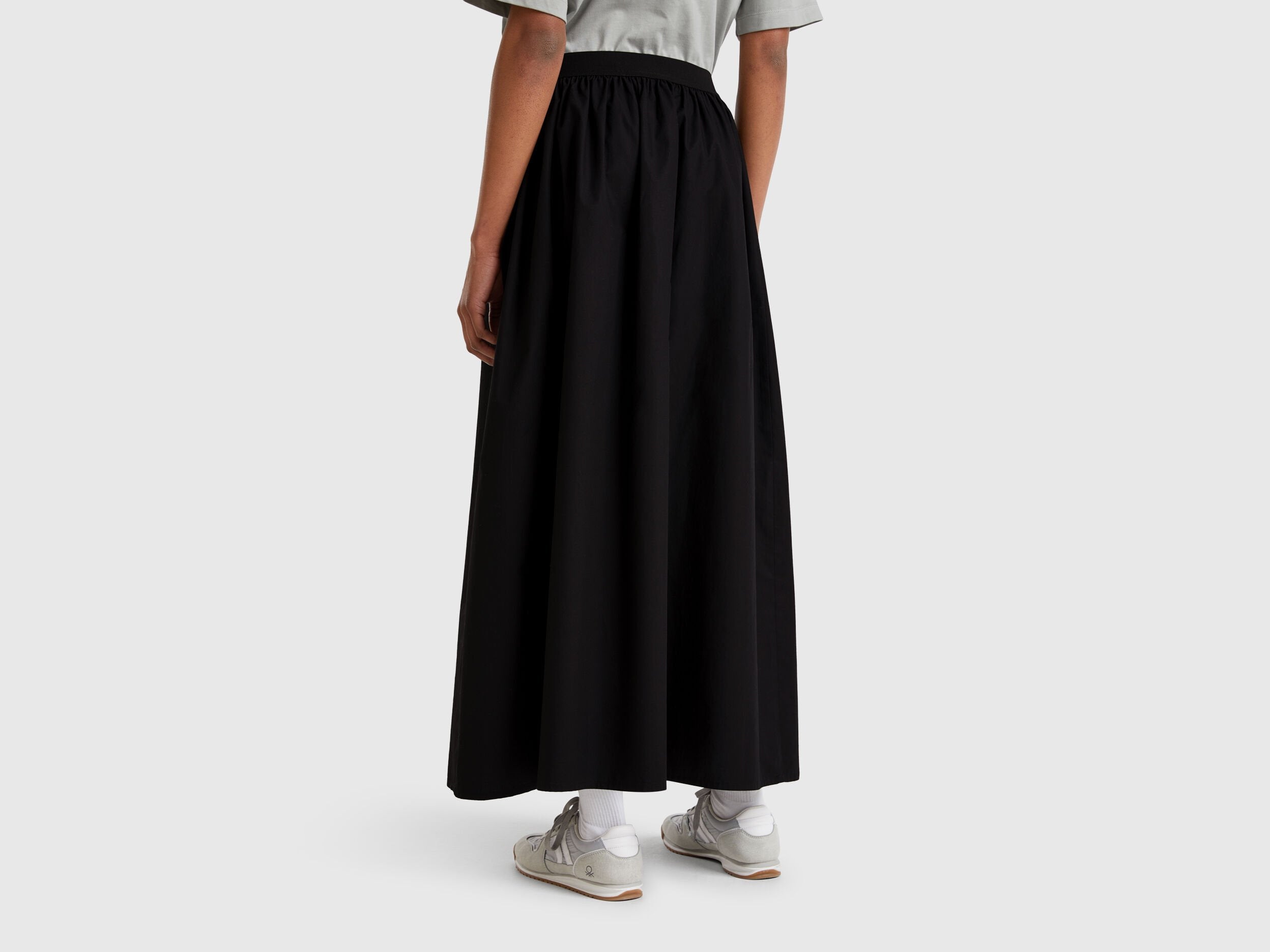 Side view of a model wearing a pink striped midi skirt and white top.