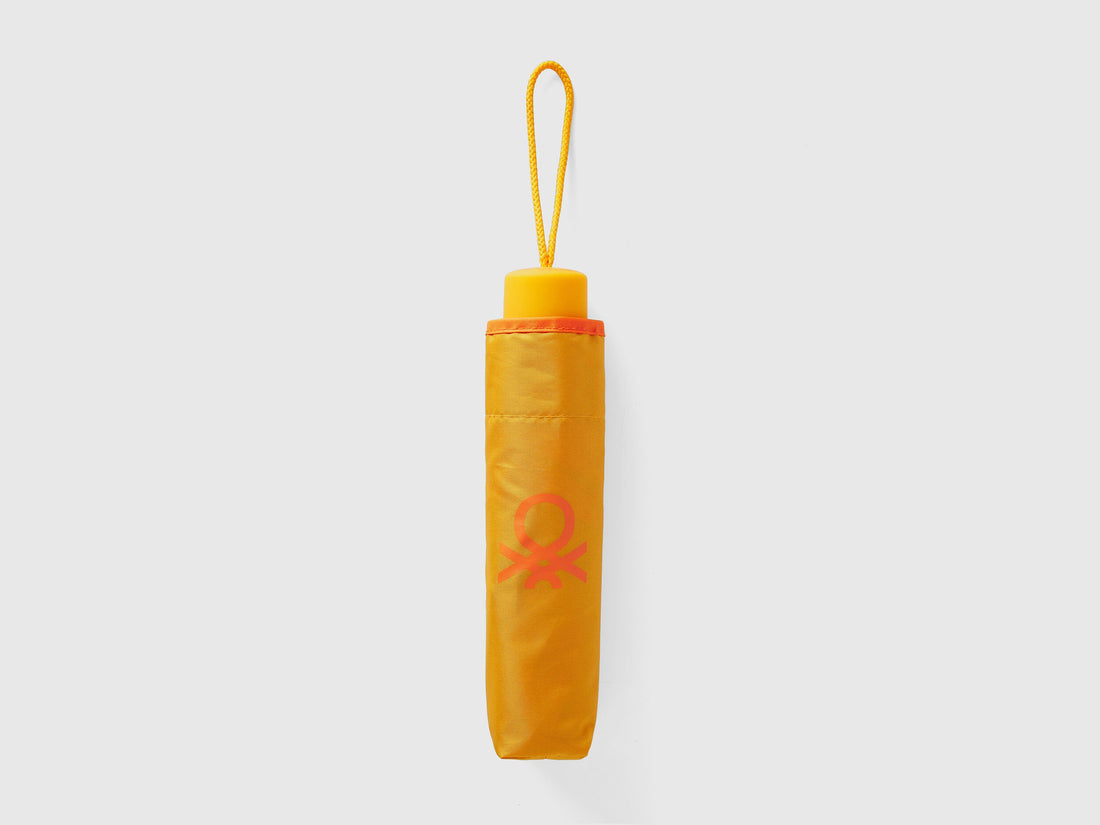 Folded yellow Benetton umbrella, compact for portability.