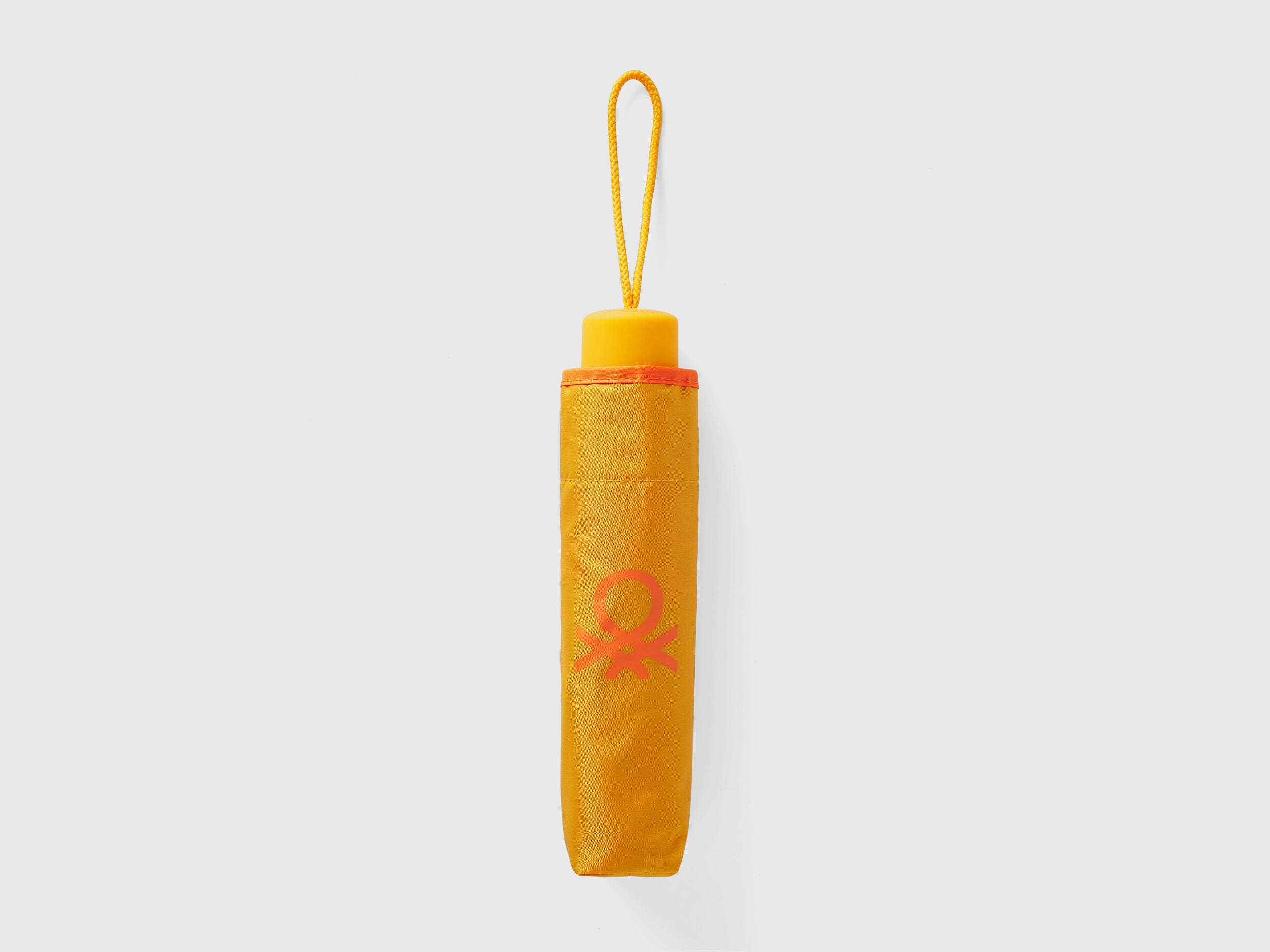 Folded yellow Benetton umbrella, compact for portability.
