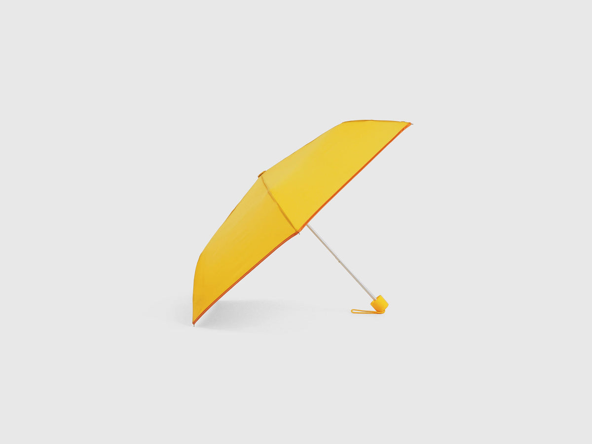 Yellow Benetton umbrella, partially open, durable design.