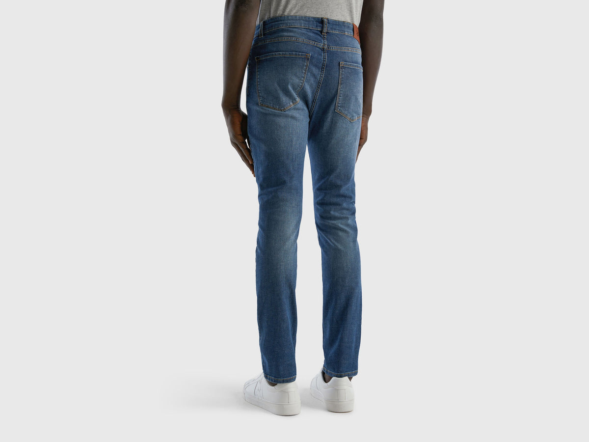 Rear view of a man wearing blue skinny jeans and white sneakers. Modern fit.