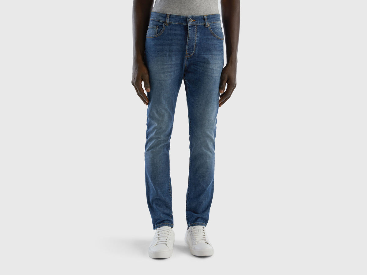 Front view of a man wearing blue skinny jeans and white sneakers. Slim fit, comfortable.