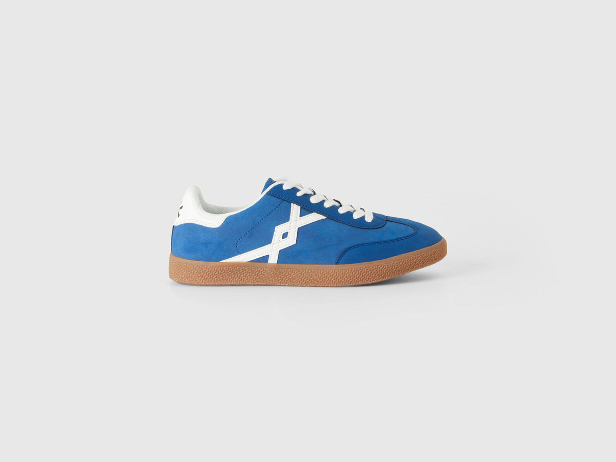 Side profile of a single cornflower blue low-top sneaker with white laces and a brown gum sole, showcasing stylish cornflower shoes in Kuwait.