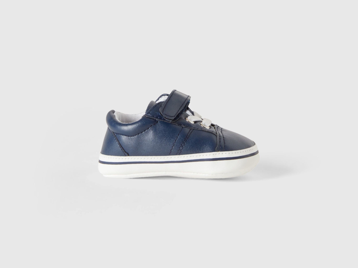 A single first-step kids shoe with a white sole and velcro strap, designed for comfort and early walkers in Kuwait.