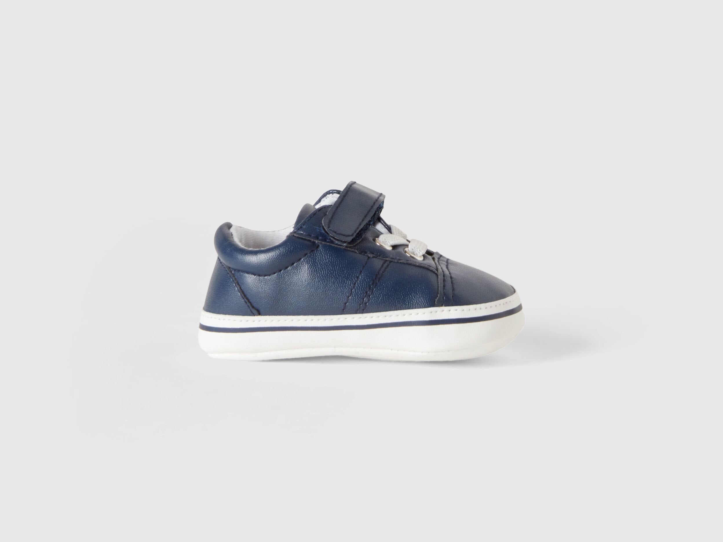 A single first-step kids shoe with a white sole and velcro strap, designed for comfort and early walkers in Kuwait.