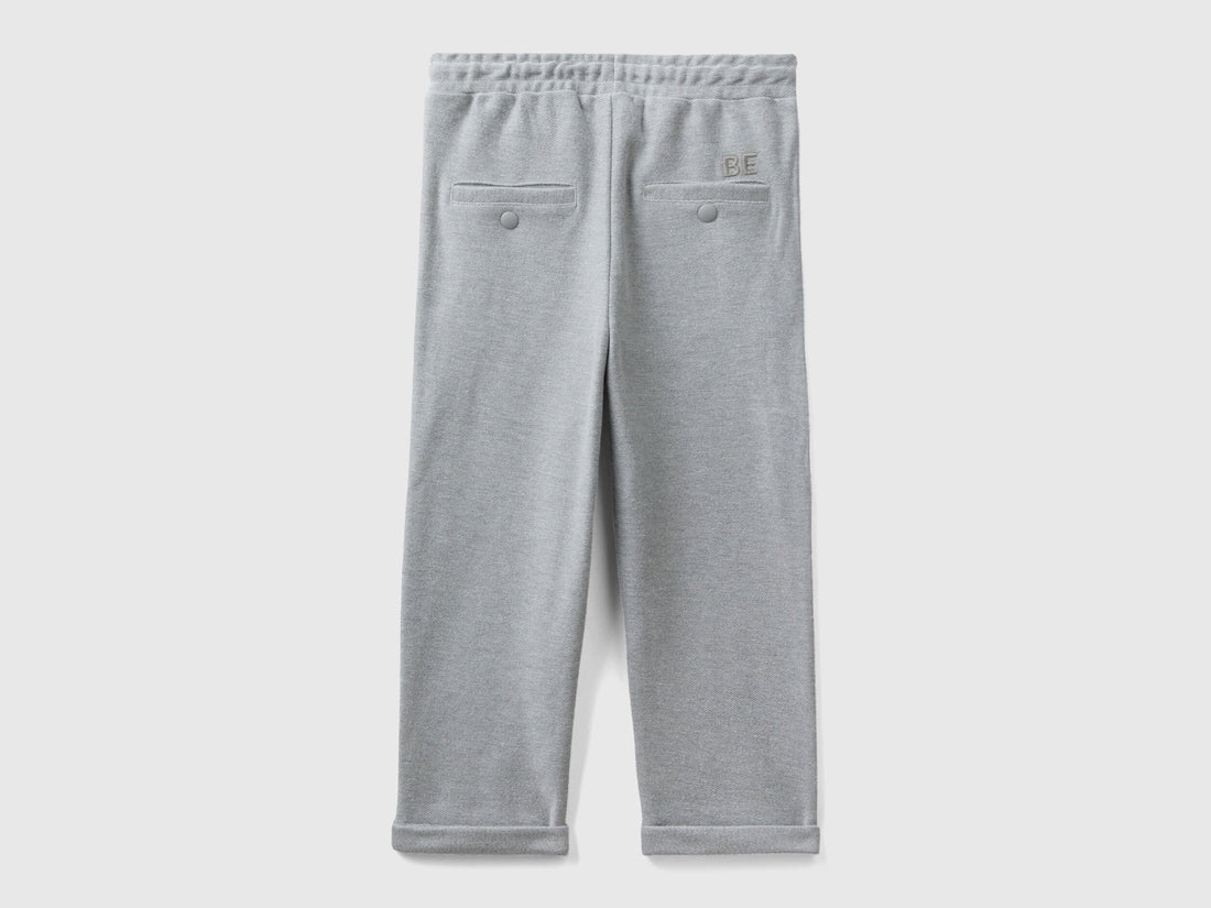 Back view of folded grey carrot fit joggers with subtle embroidery.