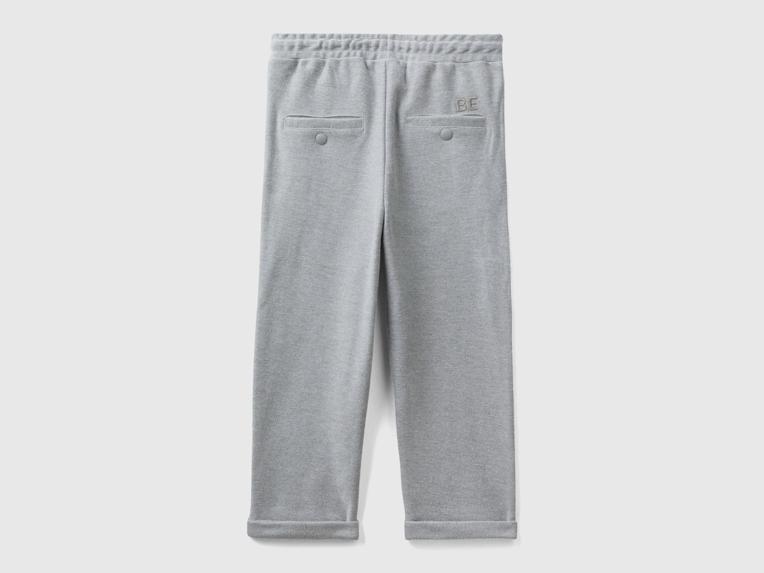 Back view of folded grey carrot fit joggers with subtle embroidery.