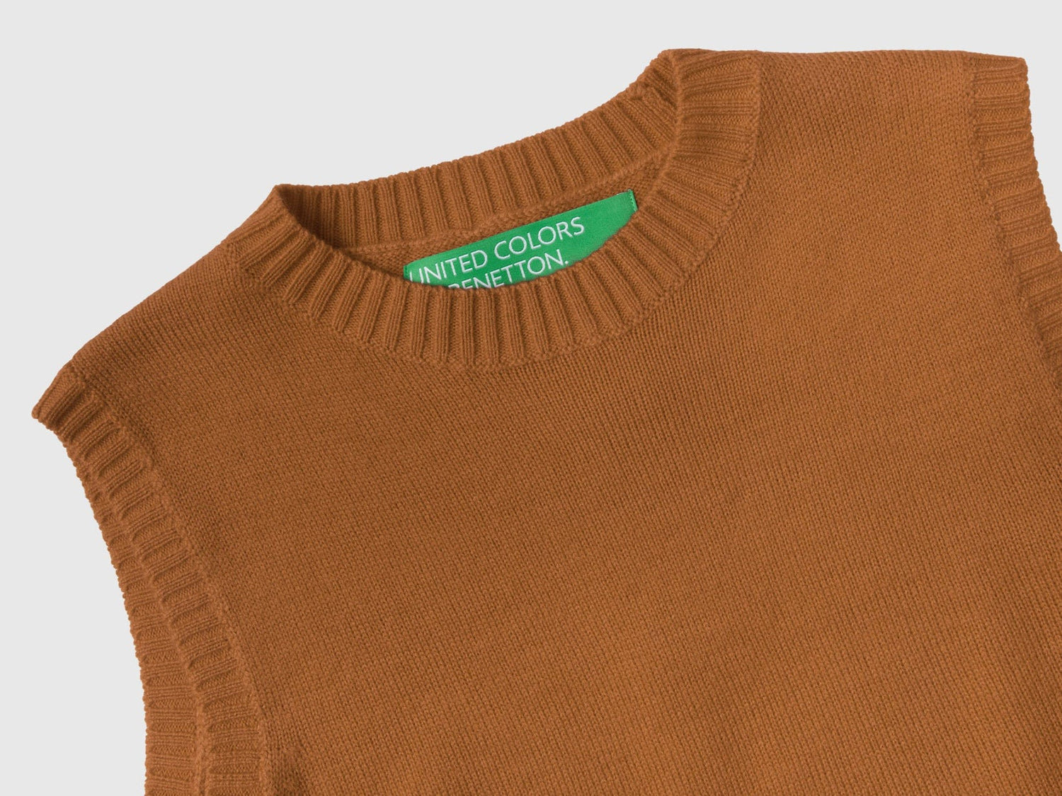 Close-up of a light brown knit vest showing the United Colors of Benetton label.