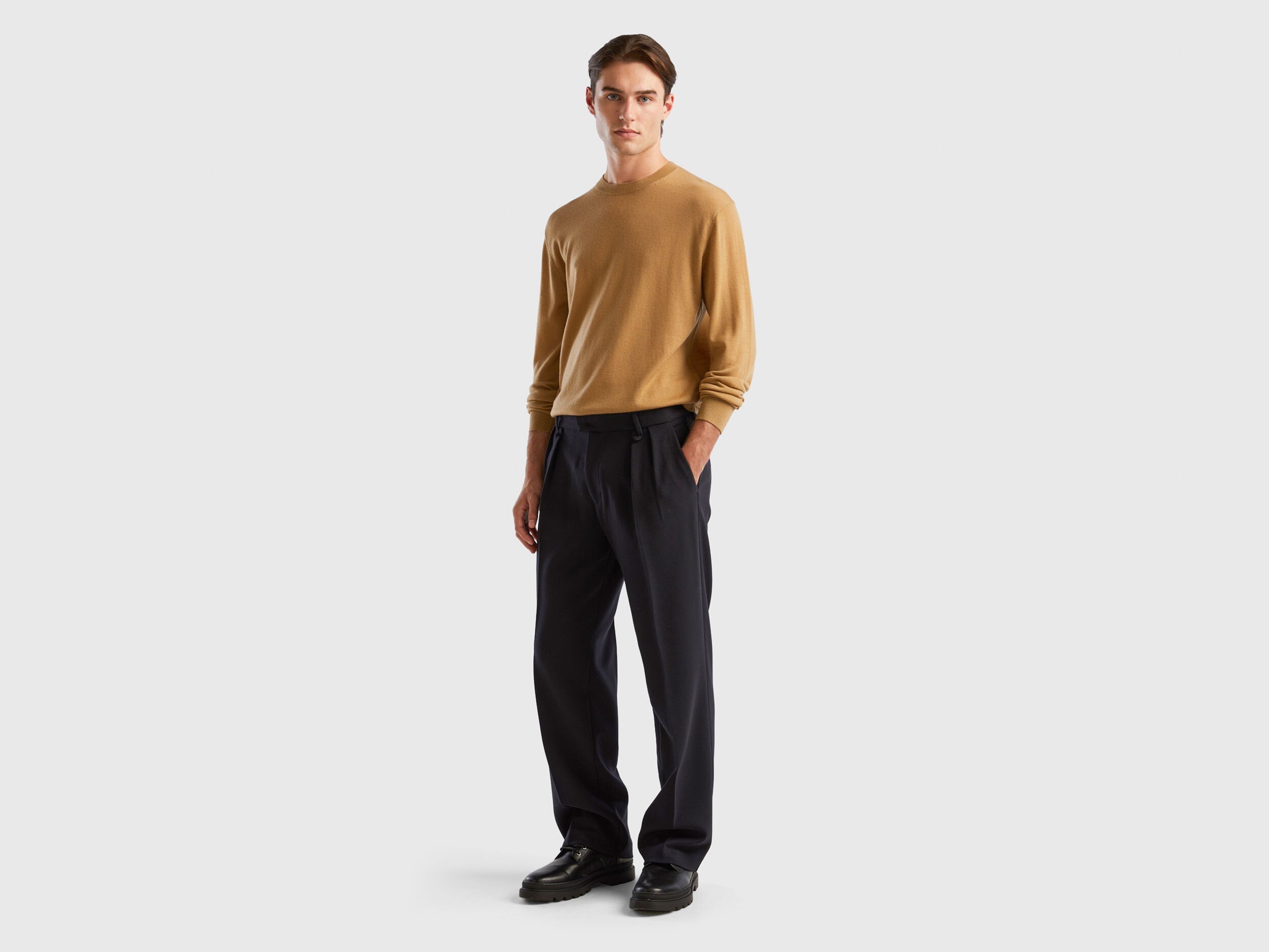 Side view of a man wearing a plain beige sweater.