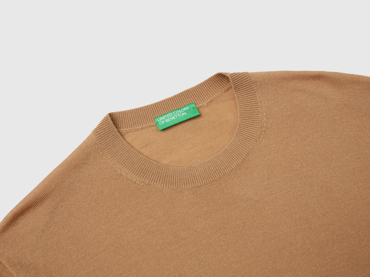 Close-up of the ribbed cuff and texture of a beige sweater for men.