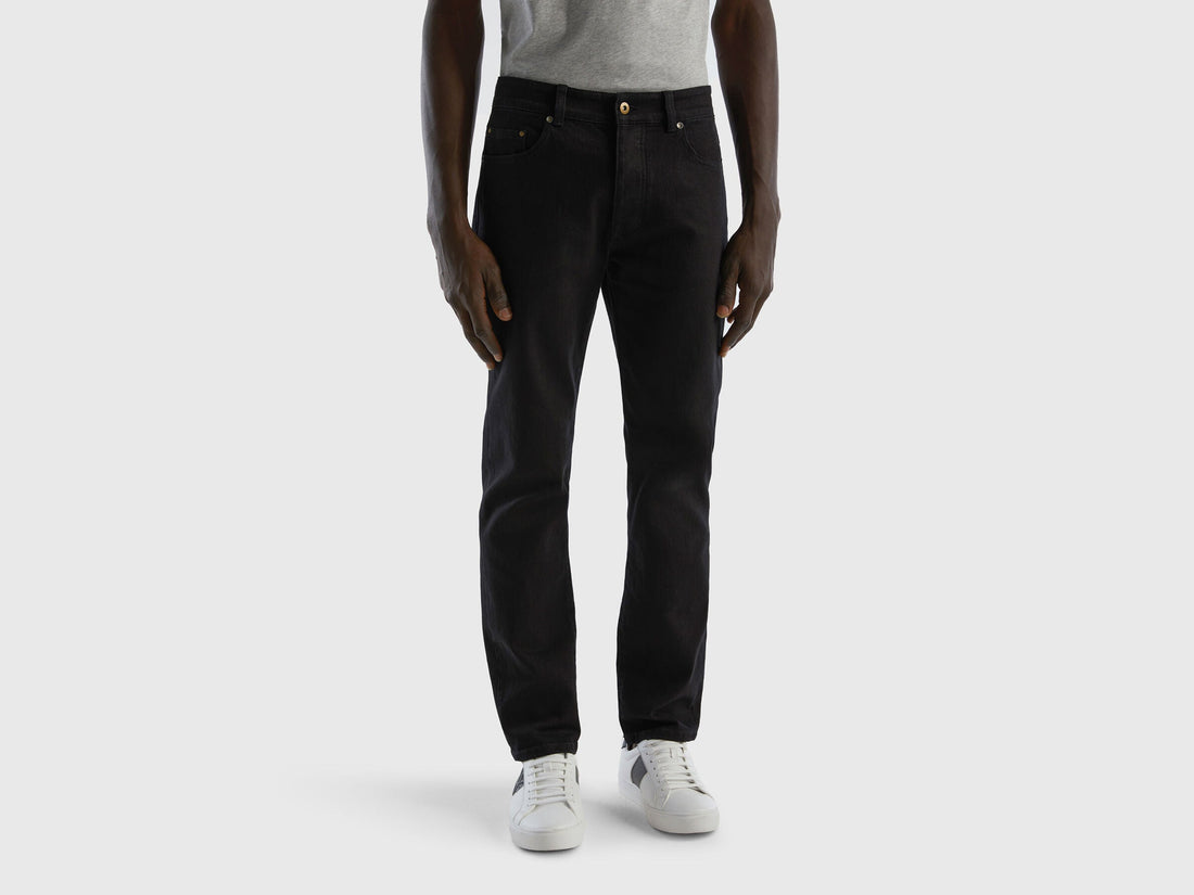 Full-length back view of a man wearing black slim-fit jeans.