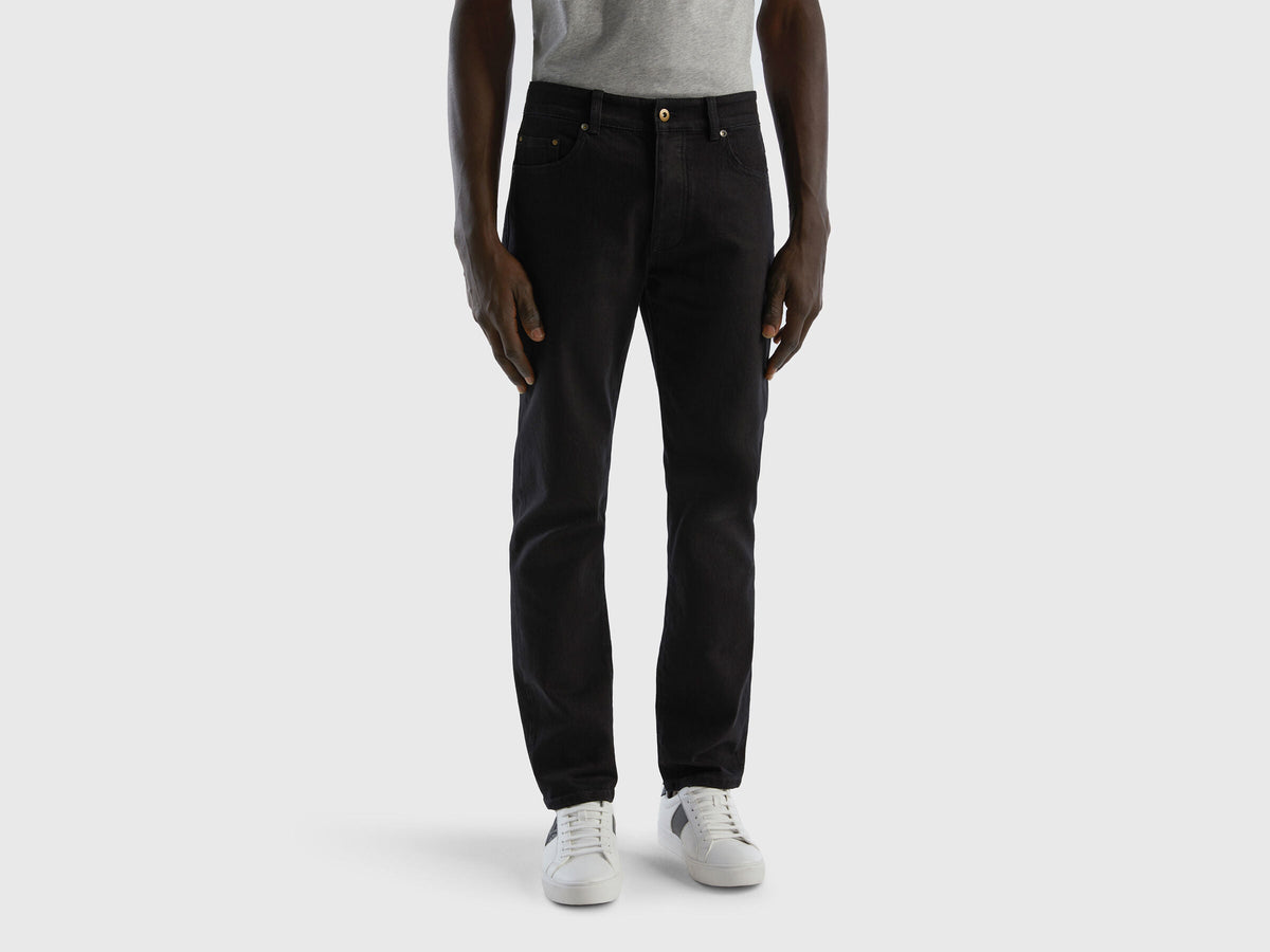 Full-length back view of a man wearing black slim-fit jeans.