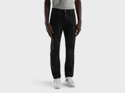 Full-length back view of a man wearing black slim-fit jeans.