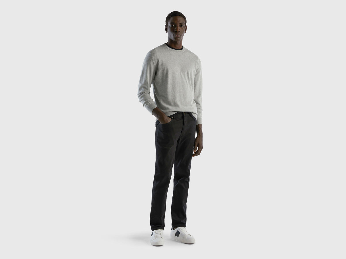 Full-length front view of a man wearing black slim-fit jeans.