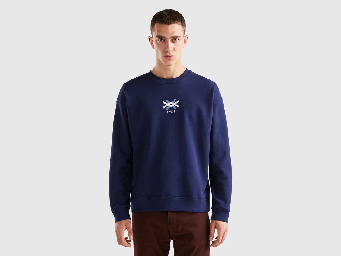 Front view of a man wearing a plain blue crew neck sweatshirt.