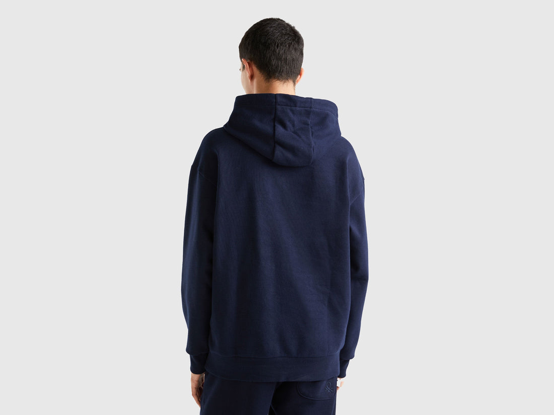 Back view of a man wearing a plain blue pullover hoodie.