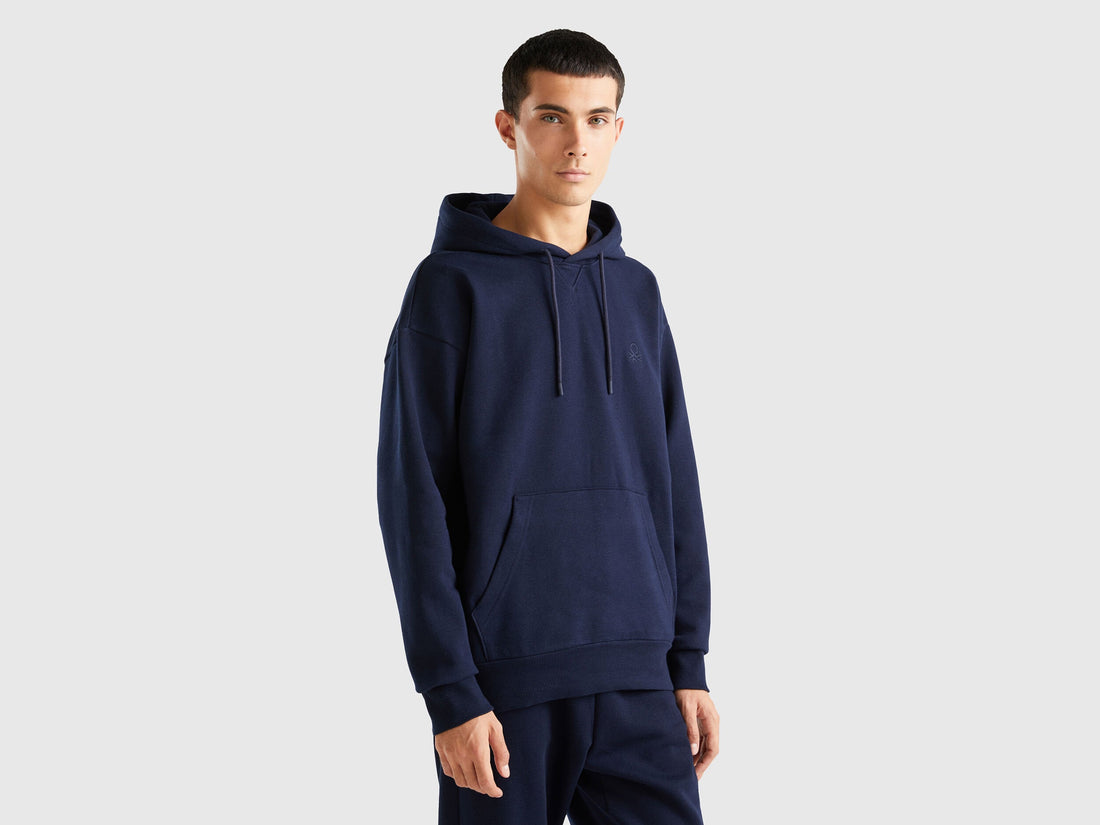 Front view of a man wearing a plain blue pullover hoodie with a kangaroo pocket.