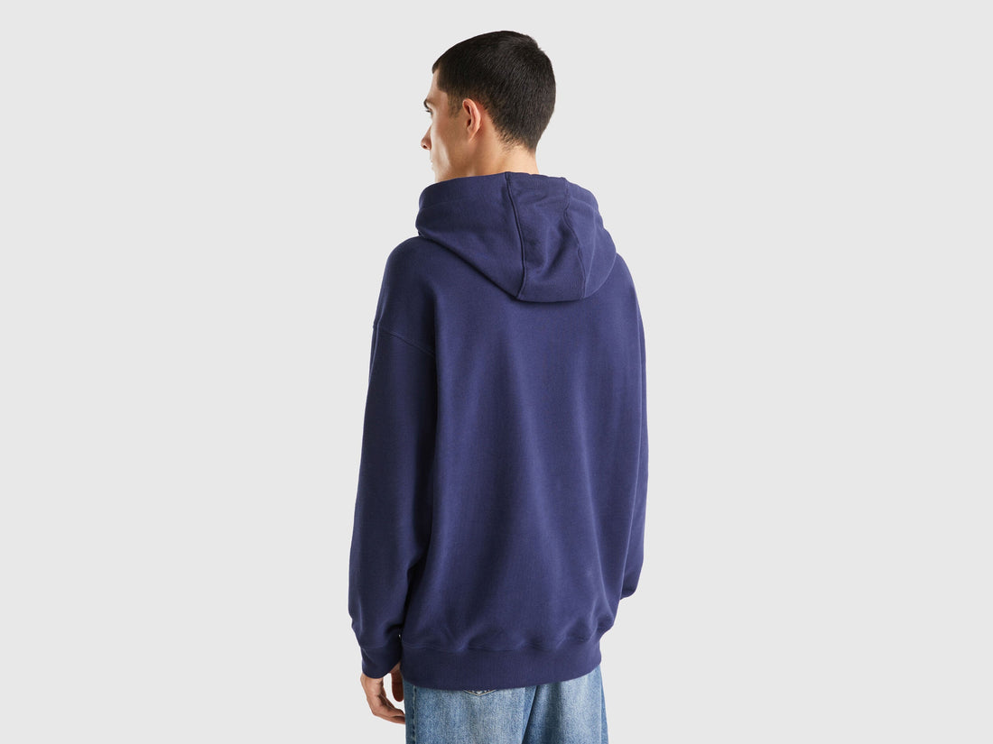 Back view of a man wearing a blue hoodie with a graphic print.