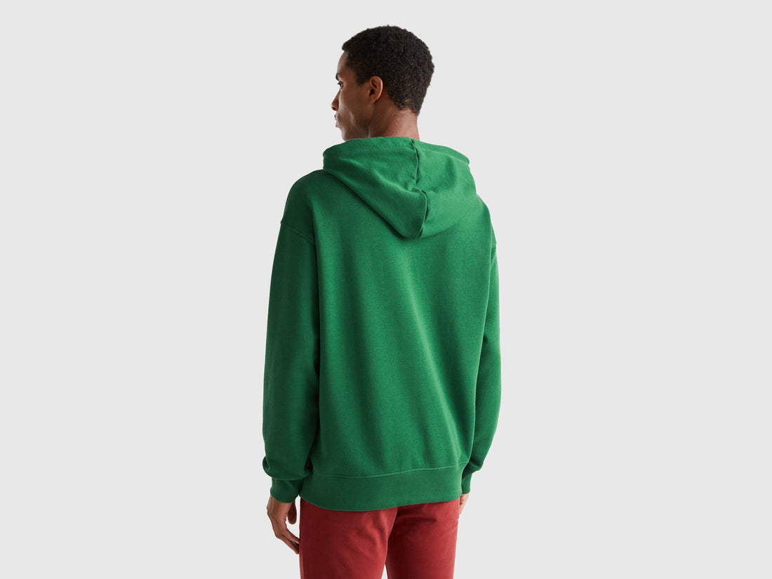 Back view of a man wearing a plain green zip-up hoodie.