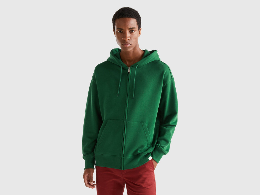 Front view of a man wearing a plain green zip-up hoodie.