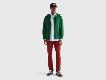 Side view of a man wearing a plain green zip-up hoodie.
