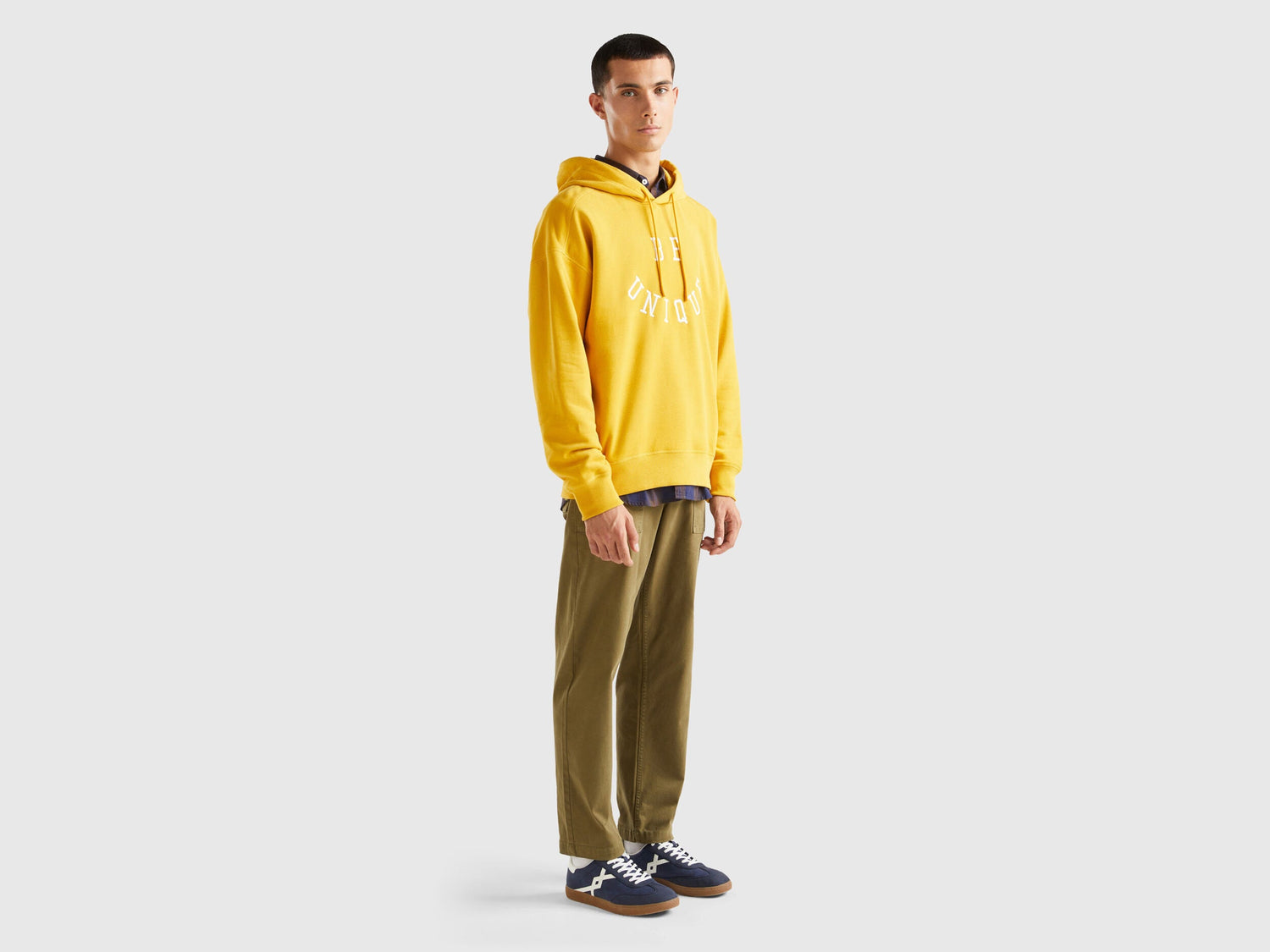 Flat lay front view of a yellow hoodie for men with a graphic print.