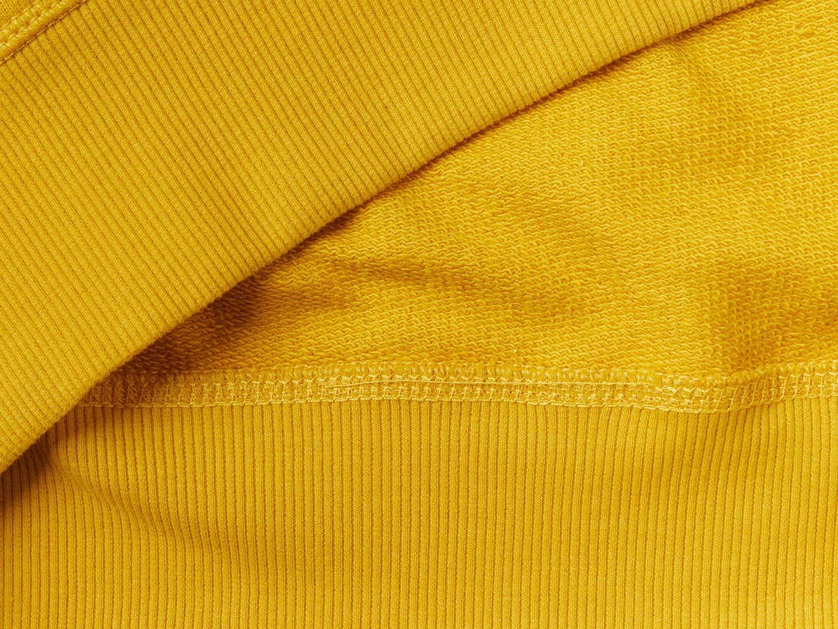Side view of a man wearing a yellow hoodie with a graphic print.