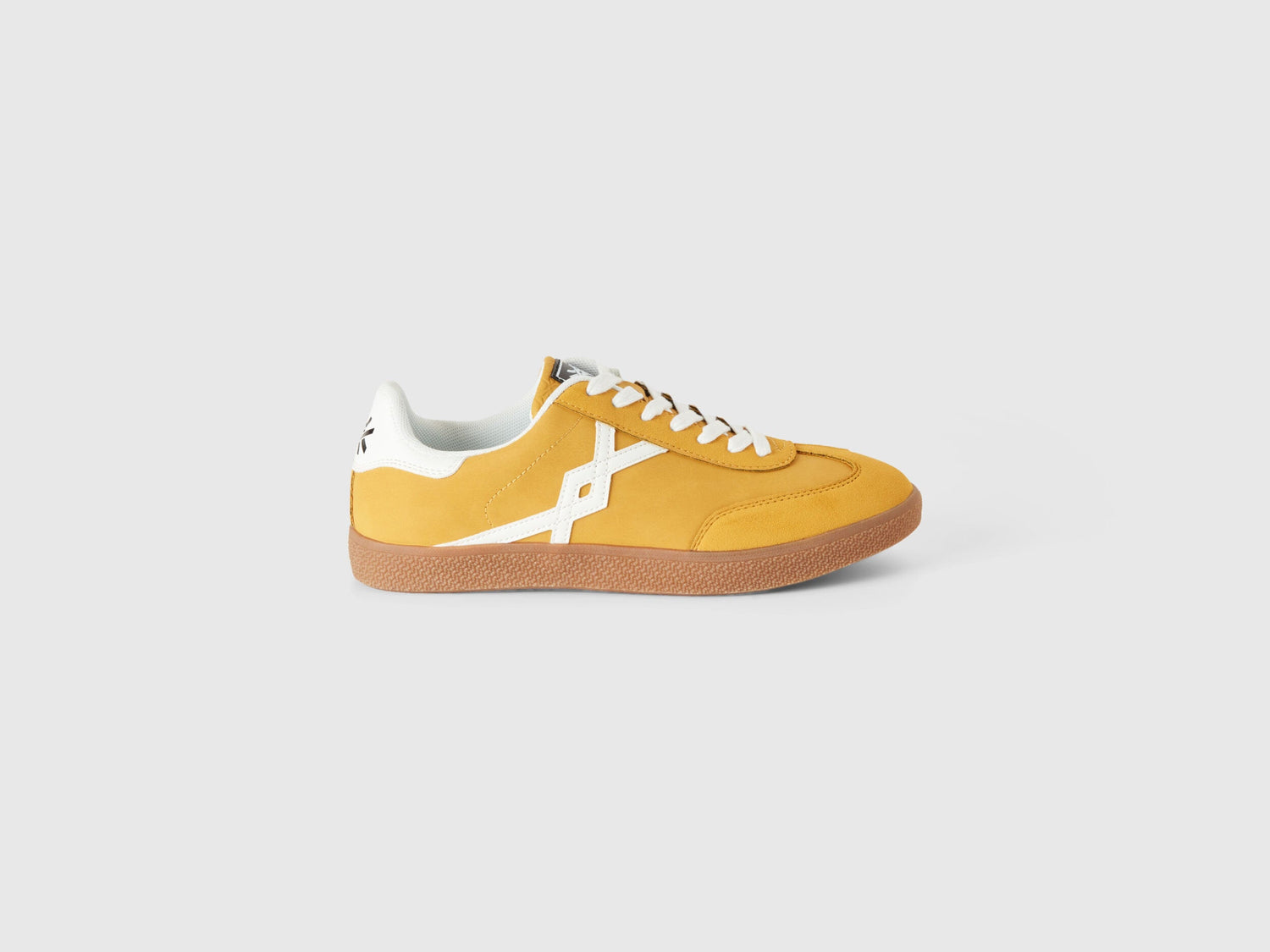 Single mustard yellow low-top sneaker with white stripe.