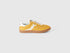 Single mustard yellow low-top sneaker with white stripe.