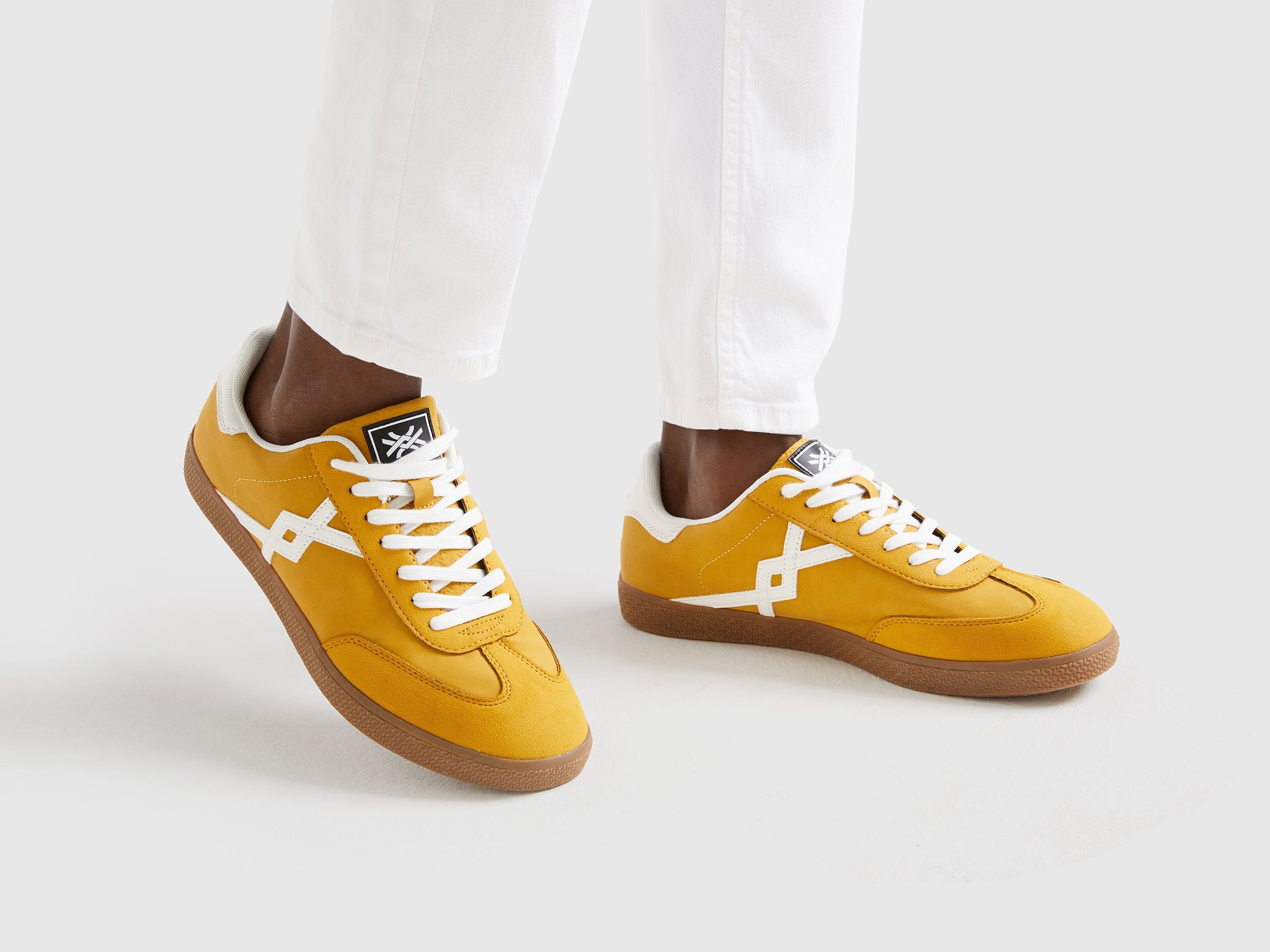 Close-up of mustard yellow low-top sneakers on a person&